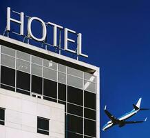 viaje y hotel concepto de avión siguiente a un edificio con un firmar escrito hotel con azul cielo foto