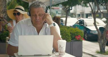 Man wearing headset video chatting in outdoor cafe