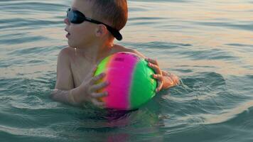 criança tomando banho dentro a mar e tendo Diversão com bola video