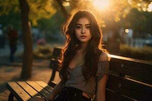 An beautiful asian woman sits on a park bench in the late afternoon photo