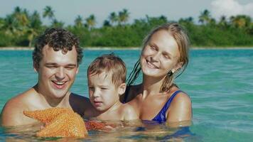Parents and son in sea water holding starfish video