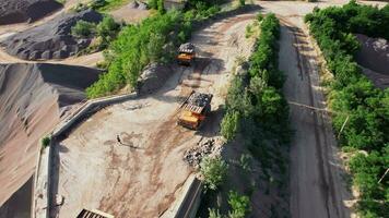 Arial view of the sand making plant in open-pit mining. Drone flies over excavators and tractor loading crushed stone and rock into dump truck. 4k stock footage. video