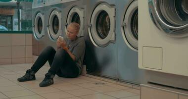 Woman with mobile waiting for the laundry video