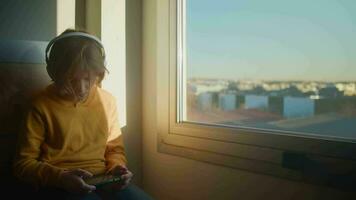 Adolescência Garoto jogando jogos em telefone às alvorecer de janela video