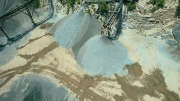 arial ver de el arena haciendo planta en a cielo abierto minería. zumbido moscas terminado excavadoras y tractor cargando aplastada Roca y rock dentro tugurio camión. 4k valores imágenes. video