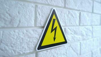 electricidad peligro un firmar en amarillo antecedentes. un peligro firmar cuelga en un pared. 4k valores imágenes. video