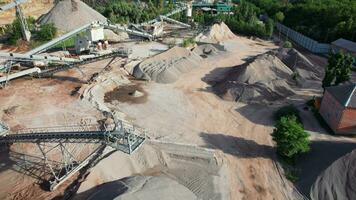 Arial view of the sand making plant in open-pit mining. Drone flies over excavators and tractor loading crushed stone and rock into dump truck. 4k stock footage. video