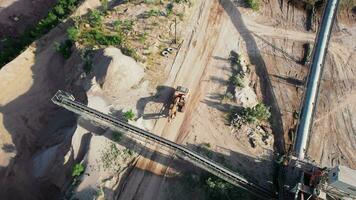 Arial view of the sand making plant in open-pit mining. Drone flies over excavators and tractor loading crushed stone and rock into dump truck. 4k stock footage. video