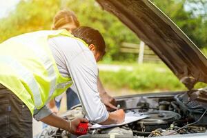 Closeup and crop auto repair checking engine and post a list of repairs according to customer orders with sun and lens flare background. photo