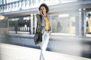 Happy young woman on the phone at the train station photo