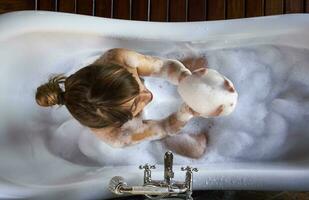 Woman playing with the foam in a bathtub, from above photo