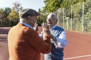 Two fit seniors high fiving on a basketball field photo