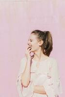 Laughing young woman in front of pink wall photo