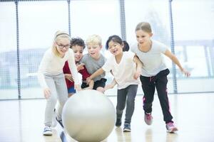 Happy pupils playing with gym ball in gym class photo