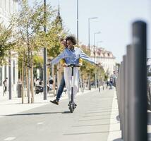 contento joven Pareja montando e-scooter en el ciudad foto