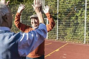 Two fit seniors high fiving on a basketball field photo