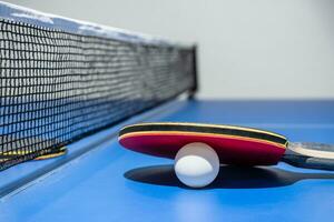 Closeup red table tennis paddle white ball and a net photo