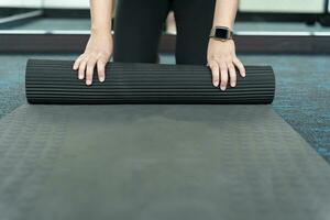 Fitness woman folding exercise mat before working out in yoga studio. rolling Yoga mat  after training healthy lifestyle photo
