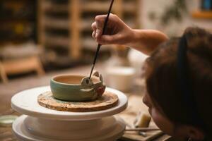 girl hands, pottery studio and painting cup in workshop for sculpture photo