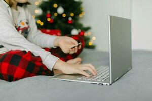 Christmas shopping online, sales during winter holidays. Girl holding card and using laptop. photo