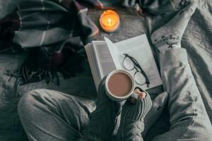 Young girl drinking hot chocolate on cozy bed. Concept of autumn or winter weekend, top view photo