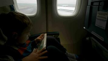Boy using tablet PC in plane going to take off video