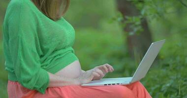 grávida mulher com computador portátil em dela joelhos video
