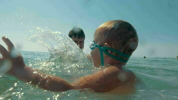 padres y niño jugando en mar y salpicaduras agua video