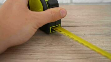 Measuring with yellow tape measure. Hands pull the measuring tape out of tape measure and measure the length. 4k stock footage. video