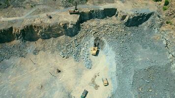 arial visie van de zand maken fabriek in open pit mijnbouw. dar vliegt over- graafmachines en trekker bezig met laden verpletterd steen en rots in dump vrachtwagen. 4k voorraad filmmateriaal. video