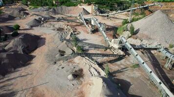 arial ver de el arena haciendo planta en a cielo abierto minería. zumbido moscas terminado excavadoras y tractor cargando aplastada Roca y rock dentro tugurio camión. 4k valores imágenes. video