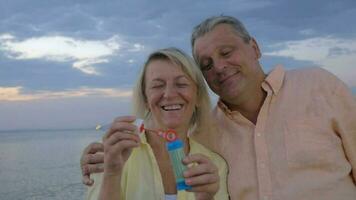 Lycklig senior par blåser bubblor på de strand video