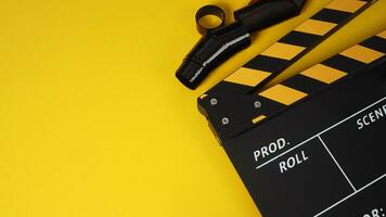 Clapper board or slate with black and yellow color and film roll on yellow background. photo