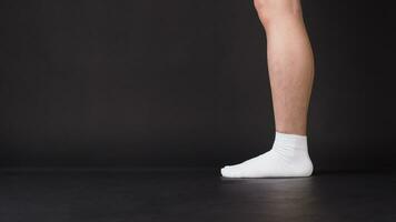 asiático masculino piernas vestir blanco calcetín es aislado en negro antecedentes foto
