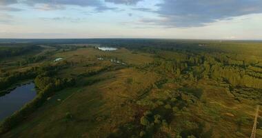 An aerial view of picturesque scenery with green fields and forests against blue sky video