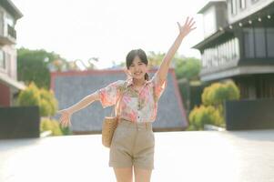 Portrait beautiful young asian woman on summer holiday vacation trip in Thailand. Young hipster female tourist sightseeing summer urban Bangkok destination. Asia summer tourism concept. photo