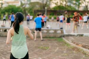 hembra persona que practica jogging. ajuste joven asiático mujer con verde ropa de deporte aeróbicos danza ejercicio en parque y disfrutando un sano exterior. aptitud corredor niña en público parque. bienestar siendo concepto foto