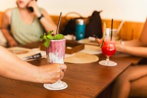 Waiter serving strawberry yogurt smoothie to customer in restaurant. photo