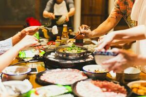 grupo de amigos Cocinando el chino shabu estofado a hogar. foto