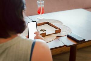 Close up of woman using cell phone on the table in restaurant. photo