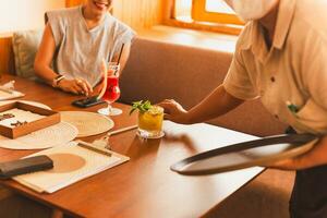 Waiter serving glass of fresh passion fruit drink in restaurant. photo