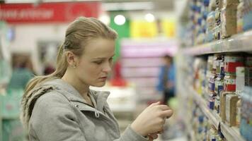 Young woman is choosing food for her child in the supermarket video