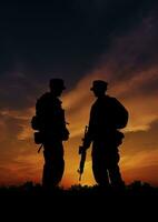 Silhouettes of Two Soldiers Standing Strong Against the Sunset Sky photo