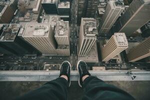 Adventurous Urban Explorer Sitting on Skyscraper Ledge with Sneakers Hanging Over Edge photo