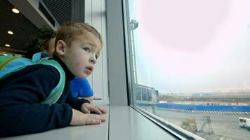 Mother and little son looking out the window at airport video