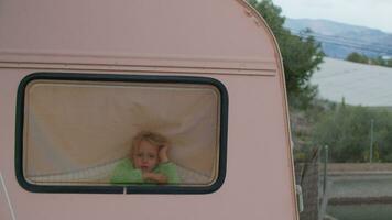 pequeño rubia niña echar un vistazo fuera de camper camioneta ventana video