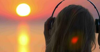 fille écoute à la musique et à la recherche à le coucher du soleil scène video