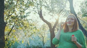 Happy pregnant woman blowing bubbles in bloomy park video