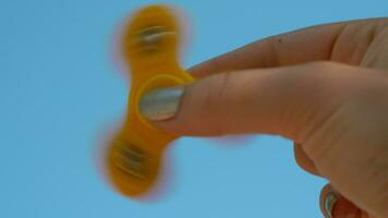 Playing with yellow fidget spinner on sky background video