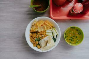 pollo fideos, sopa y chile salsa en un de madera mesa. parte superior ver de indonesio comida en de madera mesa antecedentes. foto